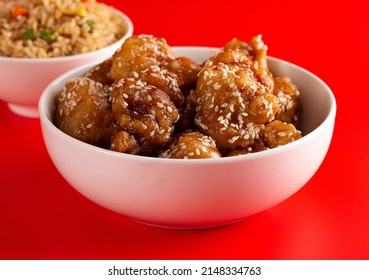 Bowl Of Sesame Chicken On A Bright Red Background