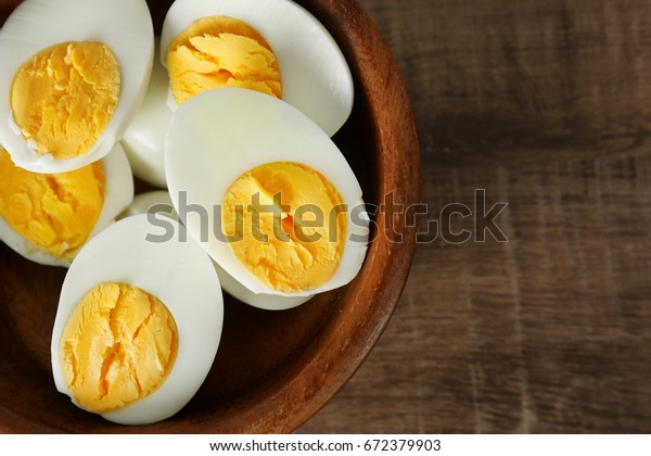 Bowl with sliced hard boiled eggs on wooden\
table. Nutrition concept