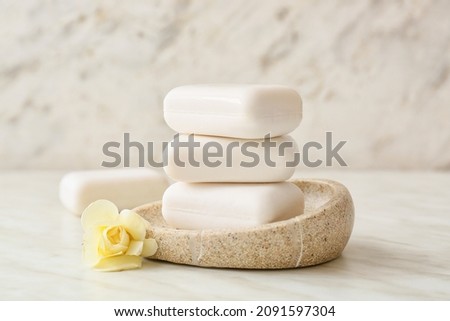 Bowl with soap bars on light background