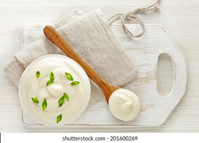 Bowl Of Sour Cream On White Wooden Cutting Board, Top View