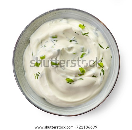 Bowl of sour cream sauce with herbs isolated on white background, top view