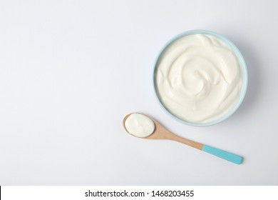 Bowl Of Sour Cream And Wooden Spoon On White Background, Top View