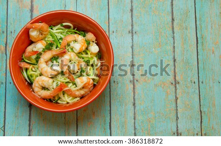 Bowl of spiralized zucchini topped with jumbo shrimp on wood plank board Stock photo © 