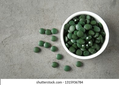 Bowl With Spirulina Tablets On Grey Table