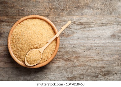 Bowl And Spoon With Brown Sugar On Wooden Background