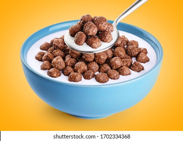 Bowl and spoon with chocolate corn balls, milk, yogurt on orange background. With clipping path.