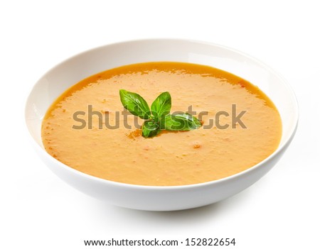 bowl of squash soup with basil leaf isolated on white