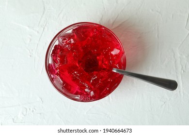 Bowl of strawberry jelly with spoon on white textured table