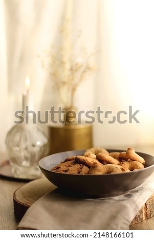 Bowl of sugar cookies and chocolate chip cookies, lit candle and vase with flowers on the table. Selective focus.