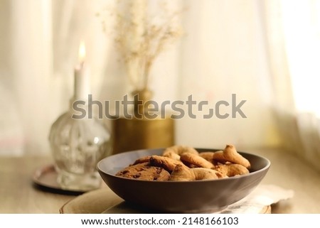 Bowl of sugar cookies and chocolate chip cookies, lit candle and vase with flowers on the table. Selective focus.