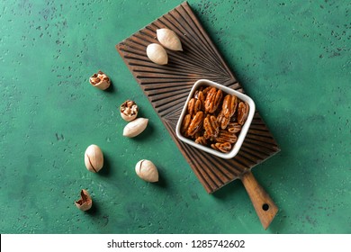 Bowl With Tasty Candied Pecan Nuts On Color Table