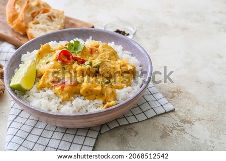 Bowl of tasty chicken curry with rice on light background