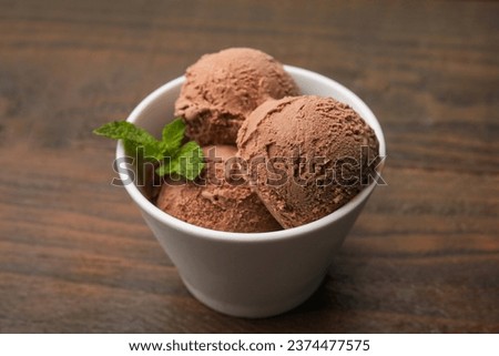 Bowl with tasty chocolate ice cream and mint leaves on wooden table