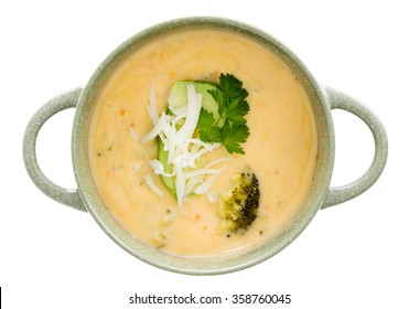 Bowl Of Tasty Cream Of Broccoli Soup Garnished With Fresh Parsley And Grated Cheddar Cheese, Overhead View Isolated On White