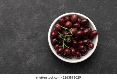 Bowl of tasty dark-purple olives on dark table. Flat lay with copy space - Powered by Shutterstock