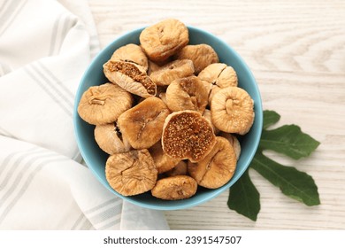 Bowl with tasty dried figs and green leaf on white wooden table, top view - Powered by Shutterstock