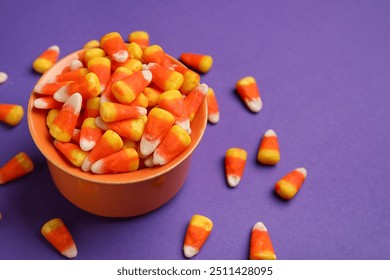 Bowl of tasty Halloween candy corns on purple background - Powered by Shutterstock