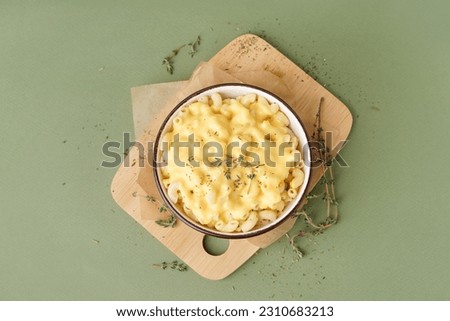 Bowl of tasty Italian pasta with Cheddar cheese on green background