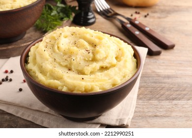 Bowl of tasty mashed potatoes with black pepper served on wooden table
