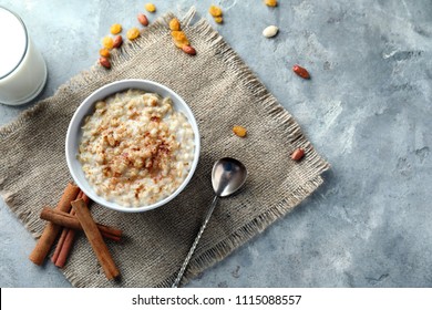 Bowl with tasty oatmeal and cinnamon on grey textured background - Powered by Shutterstock