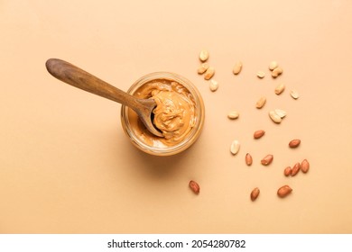 Bowl with tasty peanut butter and spoon on color background