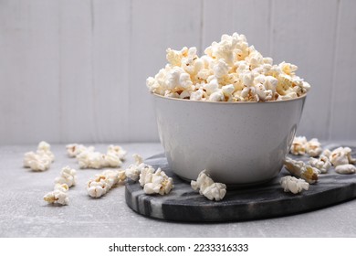 Bowl of tasty popcorn on grey table, space for text