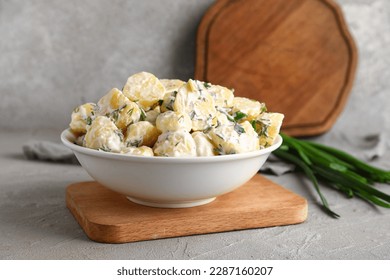Tazón de ensalada sabrosa de patata con verduras de fondo gris
