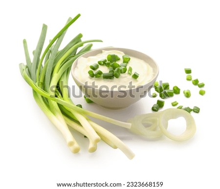 Bowl of tasty sour cream with sliced scallion and onion on white background