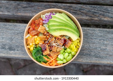 A poké bowl that is freshly made with rice, avocado, tofu, kimchi, and other fresh ingredients. Completely vegan Asian food with a lot of pickled vegetables, made in soy sauce. An Asian rice bowl