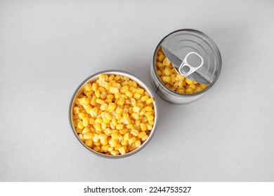 Bowl and tin can with canned corn on grey background