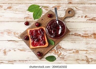 Bowl and toast with cherry jam on wooden background