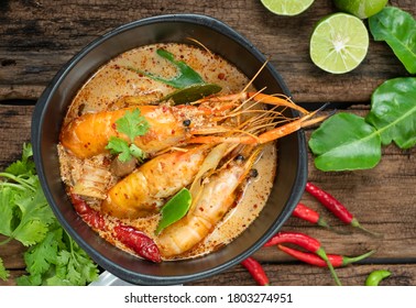 Bowl of Tom Yum Kung with herbal ingredients on wooden background. Tom Yum Kung / Tom Yum Goong is popular tradition Thai cuisine served in Thai restaurant. Spicy Thai prawn soup concept. Copy space.