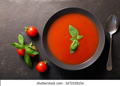 Bowl Of Tomato Soup With Basil On Dark Background, Top View