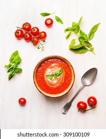 Bowl Of Tomato Soup Or Gazpacho With Spoon And Basil On White Wooden Background, Top View