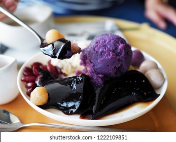 A Bowl Of Trendy Taiwanese Dessert; Taro Ball, Potato Ball, Red Bean, Grass Jelly And Scoop Of Sweet Potato Over Shaved Ice Topped With Syrup.