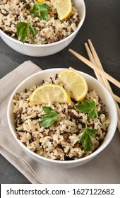 Bowl of tricolor quinoa with wild and brown rice served with lemon and cilantro garnish