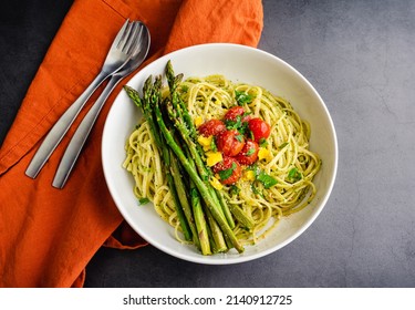 Bowl Of Tuscan Linguine Pasta All'Etrusca With Asparagus: Overhead View Of Noodles Topped With Roasted Cherry Tomatoes, Asparagus, And Egg Yolk In A Basil Sauce