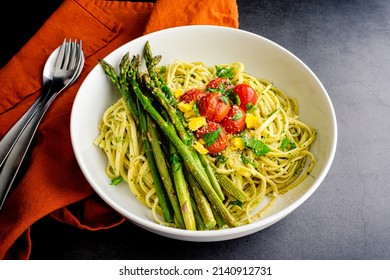 Bowl Of Tuscan Linguine Pasta All'Etrusca With Asparagus: Overhead View Of Noodles Topped With Roasted Cherry Tomatoes, Asparagus, And Egg Yolk In A Basil Sauce