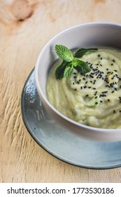 The bowl of vegan cauliflower cream soup with black cumin seeds and fresh mint 