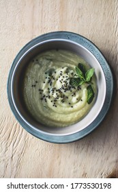 The bowl of vegan cauliflower cream soup with black cumin seeds and fresh mint 