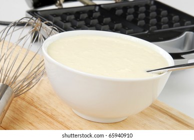 A Bowl Of Waffle Batter Next To The Waffle Iron