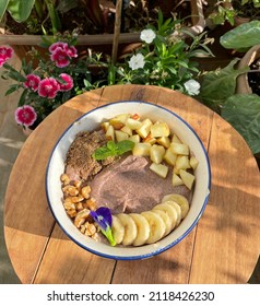 A Bowl Of Warm Ragi(finger Millet) Porridge With Chopped Bananas, Apples, Walnuts And Flax Meal On Top