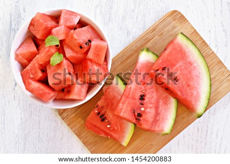 A bowl of watermelon cubes lye in a white bowl - fresh and sweet watermelon as a refreshment in summer on a white wooden surface 