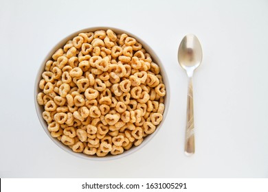 Bowl Of Whole Grain Oat Cereal With A Silver Spoon On A White Background, Top View. Heart Shapes Cereal. 