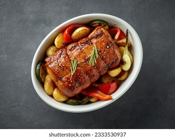 bowl of whole roast pork and vegetables on dark grey kitchen table, top view - Shutterstock ID 2333530937