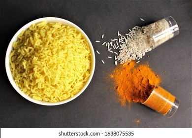 Bowl of yellow rice cooked from basmati rice with turmeric powder glass of rice,turmeric power beside the bowl. photo isolate on black top view 