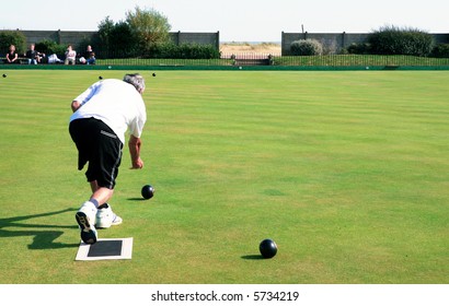 A Bowler Playing On The Village Green. Bowls Is A Traditional British Game. The Faces Of The Spectators Are Unrecognisable.