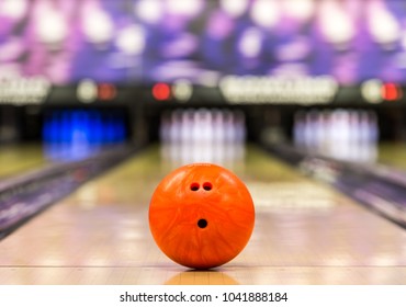 bowling ball ready to roll on a bowling lane with 10 pins in the background