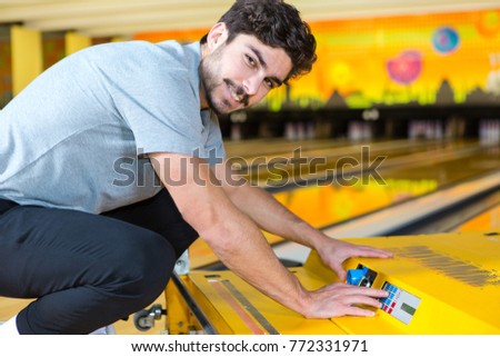 bowling employee manipulating machine to clean the alleys