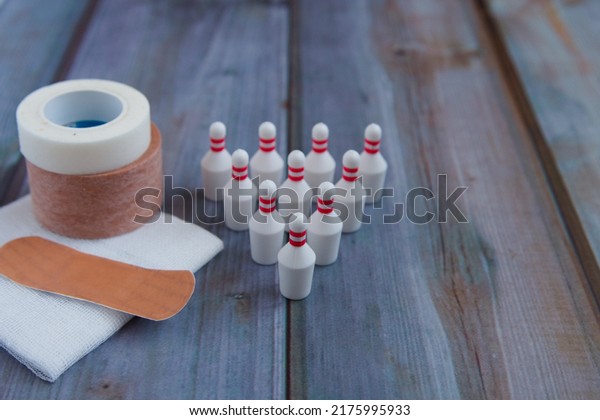 Bowling pin, surgical tape, gauze, adhesive\
plaster and wooden background to the\
left